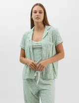 Set de pijama de tres piezas en color verde menta con estampado floral sutil, compuesto por una camisa de manga corta con botones, una musculosa básica y un pantalón largo de corte recto con cordón ajustable en la cintura.