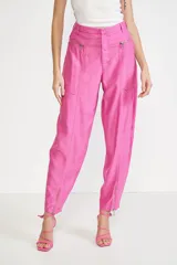 Pantalón de vestir rosado con corte holgado, tiro alto, bolsillos laterales con cierre y cierres en los tobillos.