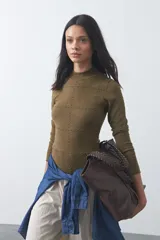 Polera de tejido de punto color celeste, con cuello alto y textura de pequeños puntos en relieve formando una cuadrícula en el frente y las mangas. De corte ajustado y manga larga.