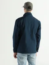 Campera azul marino de poliéster, tipo softshell, con cuello alto y cierre frontal. Cuenta con bolsillos laterales con cierre y un bolsillo vertical en el pecho. No tiene capucha.