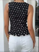 Top negro con lunares blancos, sin mangas, con escote redondo y detalle de fruncido en la cintura.