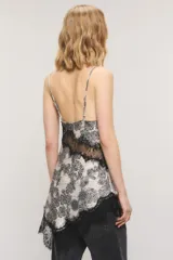 Top de satén con estampado estilo paisley en tonos blanco y negro, corte al bies, escote en V con apliques de encaje negro en el escote y el ruedo asimétrico. Cuenta con breteles regulables y tirantes finos.