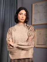 Buzo de cuello alto color gris, de manga larga, con detalle de bordado floral con lentejuelas en el hombro y parte superior de la manga.