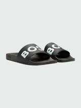 Sandalias tipo ojota Boss de color negro, con banda ancha superior que presenta el logo de la marca en letras blancas.