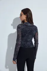Body de mangas largas con cuello alto, confeccionado en tejido de tul semitransparente con estampado animal print en tonos grises y negros.