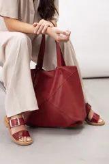 Sandalias de cuero marrón, con diseño de dos fajas amplias, una lisa en la parte delantera y otra superior con hebilla metálica grande y ajustable. Suela plana con plataforma baja y pespunte visible.