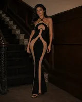 Vestido largo y ajustado color negro, con detalles de tul beige que crean un diseño geométrico, escote halter cruzado y silueta sirena.