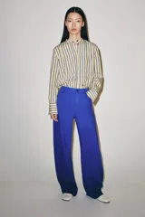 Jeans de tiro medio y corte barrel leg, de color azul, con diseño de cinco bolsillos y trabillas en la cintura. Cierre frontal con cremallera y botón metálico.
