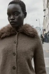 Chaqueta de punto color marrón con cuello de solapa desmontable en pelo sintético. Presenta cierre frontal con botones, manga larga y terminaciones en rib.