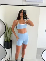 Conjunto deportivo de dos piezas celeste con detalles en blanco, compuesto por un top deportivo de escote redondo y un short corto de talle alto.