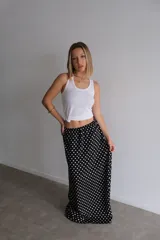 Pollera larga de fibrana color bordó con estampado de lunares blancos, tiro alto y corte amplio.