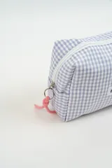 Neceser de tela con estampado de cuadros vichy en color verde y blanco. Cuenta con una etiqueta frontal con el logo de la marca y un tirador de cierre en color rosado.