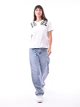 Remera blanca de manga corta con cuello redondo, destacada por apliques bordados con lentejuelas en los hombros.