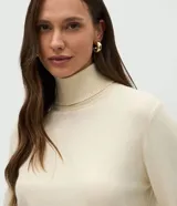 Suéter de punto color crema con cuello alto y mangas largas. Presenta un diseño ajustado al cuerpo con puños acanalados.
