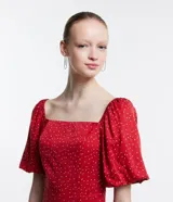 Vestido corto rojo con lunares blancos, escote cuadrado, mangas cortas abullonadas y abertura lateral en la falda.