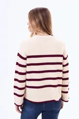 Buzo tejido de punto con diseño a rayas horizontales en color crema y bordó, de cuello redondo y mangas anchas.