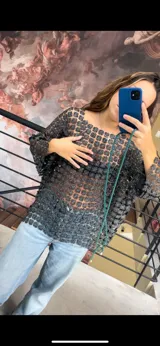 Blusa de red con diseño calado de flores pequeñas en tono plateado y negro, de corte holgado y mangas anchas.