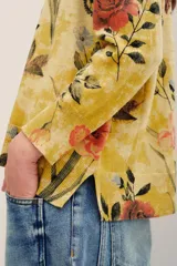 Sweater de punto color mostaza con estampado floral y de mariposas, cuello redondo y mangas largas.