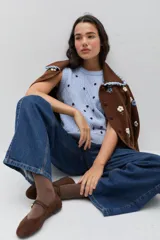 Saco de punto color bordó con bordados artesanales de flores en tonos rosados. Presenta un cuello con detalle de volados en color crema y cierre frontal con botones. De silueta amplia y cómoda.