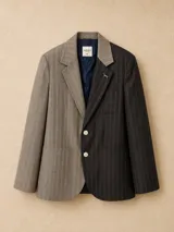Blazer oversize de diseño bicolor con estructura asimétrica, combinando un lado en color negro y otro en color marrón, ambos con estampado de rayas diplomáticas. Presenta solapas clásicas, cierre frontal con botones de strass y un pin decorativo en forma de perro salchicha.