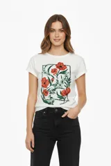 Remera blanca de manga corta con cuello redondo y calce holgado, con un estampado central de flores rojas y follaje verde enmarcado por puntos.