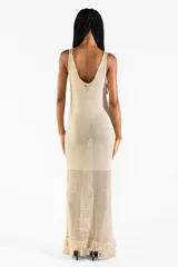 Vestido largo de punto abierto con sutil brillo dorado, escote en V y diseño sin mangas con detalles de flecos en el ruedo.