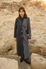 Tapado largo de sastrería con diseño bicolor, combinando dos tonos de tela con estampado de rayas diplomáticas. Presenta cierre frontal con botones de nácar, bolsillos con tapa y abertura central en la parte trasera.