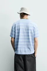 Remera relaxed fit con diseño de rayas horizontales en tonos celestes y blancos, cuello redondo y manga corta, con efecto lavado.