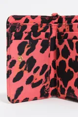 Billetera de tamaño mediano confeccionada en nylon, con cierre de cremallera y tirador de cordón. Presenta estampado animal print en tonos fucsia y negro, con logo metálico dorado en el frente.
