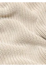 Sweater de punto en color beige, con cuello alto y cierre frontal parcial. Diseño de manga larga con puños y ruedo acanalados.