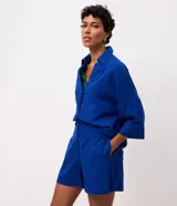 Short de corte recto confeccionado en viscolino, color azul, con cintura trasera elástica, tapetas frontales con botones decorativos, cierre oculto y costura marcada.