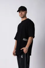 Remera de corte oversize color negro, con cuello redondo y mangas cortas. Presenta un pequeño estampado en color blanco en la parte inferior lateral con la frase 'Curbside Treasures'.