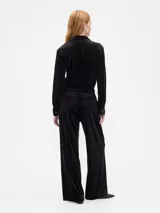Pantalón de tiro medio y corte recto, confeccionado en terciopelo negro con cintura elástica y bolsillos laterales.