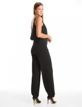 Enterito de crepe negro con diseño de capa suelta en el torso, escote en V y breteles finos ajustables. Presenta cintura definida y pantalón de pierna ancha con caída fluida, con cierre invisible en la espalda.