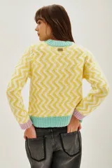 Sweater de punto con diseño de zigzag en tonos amarillo y blanco, cuello redondo, puños en color lila y ruedo en color verde menta.