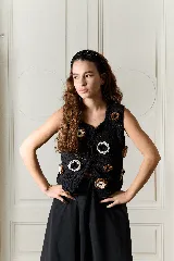 Chaleco negro tejido a crochet en 100% algodón, de calce relajado, con lazos en el frente y aplicaciones de flores orgánicas en relieve de colores blanco y marrón.
