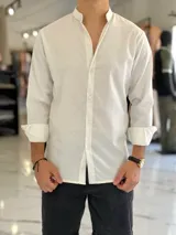 Camisa de lino blanca de manga larga con cuello mao y cierre frontal de botones.