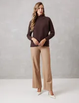 Buzo de tejido acanalado color blanco, con cuello alto y diseño de patrón en V en el frente. Presenta un corte holgado con mangas integradas sin costura de sisa.