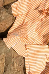 Camisa de manga corta oversize en lino rayado, con cuello camisero, cierre frontal con botones y bordado playero en el frente.