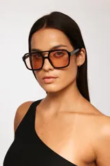 Lentes de sol con armazón de policarbonato negro y cristales tintados en tono ámbar, con diseño de estilo retro y protección UV400.