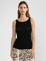 Top tejido sin mangas en punto canalé, color negro con hilos metálicos Lurex que le dan un brillo sutil. Presenta escote bote y un dije metálico en color oro rosado.