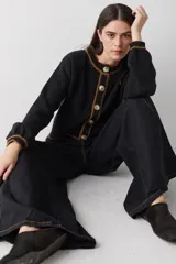 Cardigan de punto color marrón con detalles de ribete en color verde oliva en cuello, puños, ruedo y tapeta de botones. Presenta cierre frontal con botones grandes y un pequeño bordado en el pecho.