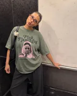 Remera de algodón con efecto lavado stone wash en color verde oliva. Presenta un diseño gráfico frontal inspirado en la película Pink Flamingos, con la imagen de Divine y tipografía estilo vintage.