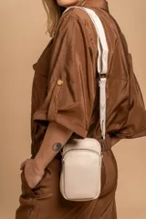 Bandolera compacta color rojo con textura de cuero, correa regulable y desmontable con diseño de rayas rojas y blancas. Cuenta con bolsillos frontales y cierre, interior forrado en tela.