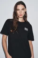 Camiseta negra de manga corta y cuello redondo, con estampado pequeño en blanco en el pecho que dice "1974 FR. ARCHIVE".