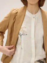 Blazer de lino color marrón con solapa chal y costuras pespuntadas a contratono en color rojo. Presenta bolsillos frontales ojal y un botón de cierre.