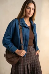Campera bomber de jean con corte oversize, cierre frontal y cuello alto con botones a presión. Presenta mangas amplias y puños ajustados.