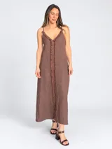 Vestido maxi largo de lino color marrón, con escote en V, tirantes finos regulables y detalles de flecos en los bordes y en la parte frontal.