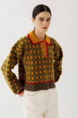 Buzo de tejido de punto con diseño de rombos en tonos beige y marrón. Presenta cuello polo con cierre frontal de tres botones, mangas largas con puños acanalados y ruedo también acanalado.
