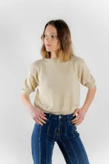 Sweater color dorado de tejido de punto suave con hilos metalizados, corte recto y mangas cortas con puño ajustado.